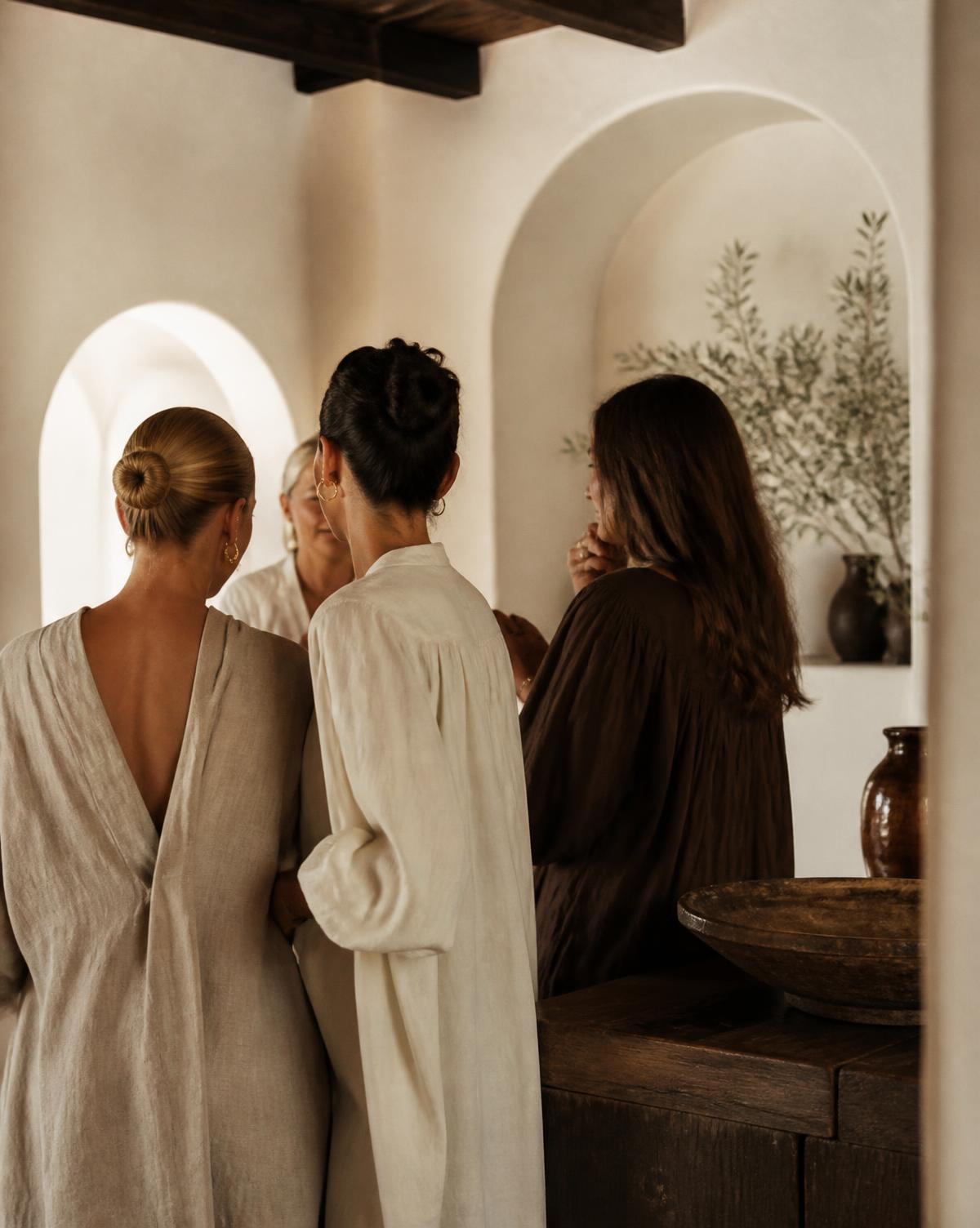 Women in linen gathered in a sunlit Mediterranean room